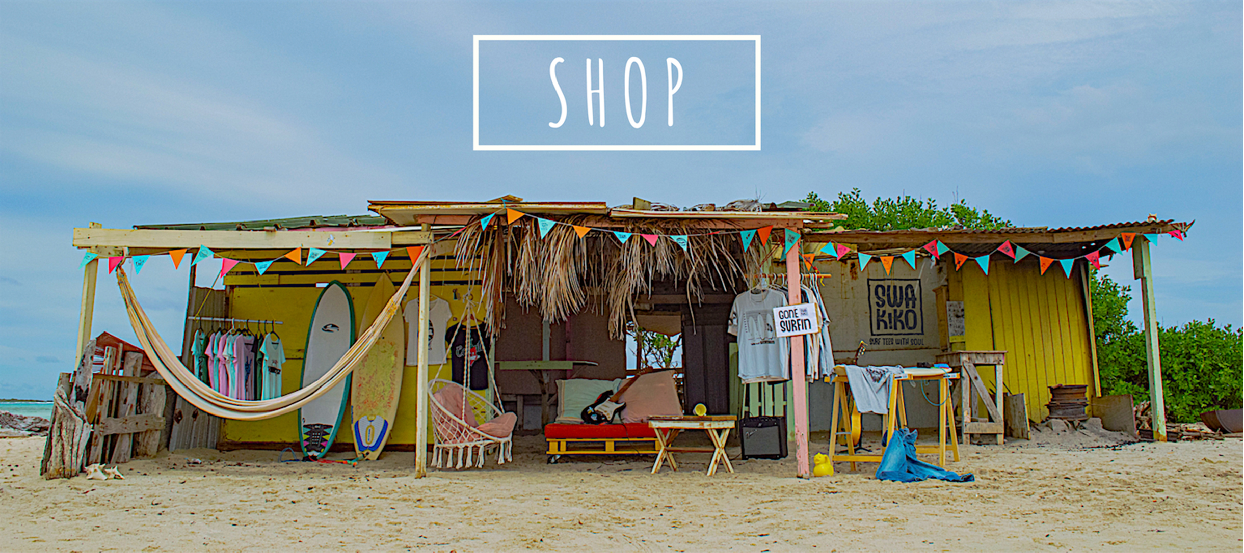 Kleurrijke SWAKiKO surf shop op het strand bij Sorobon op Bonaire, volledig ingericht met surfboards, shirts en slingers